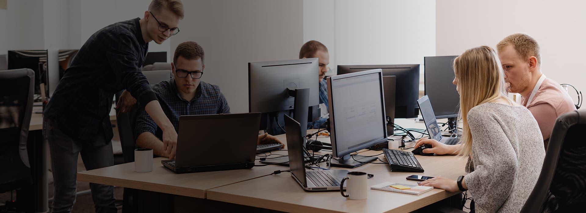Equipo de trabajo colaborando frente a computadores en una oficina moderna